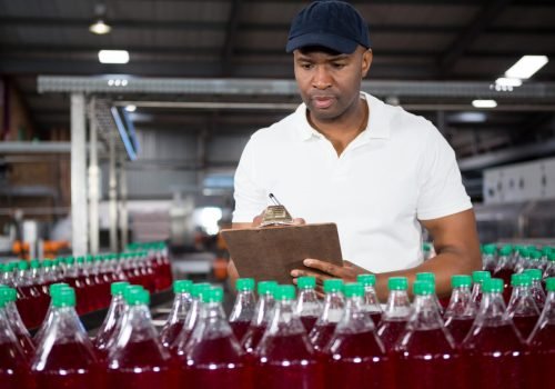 Confident male worker writing on clipboard in factory